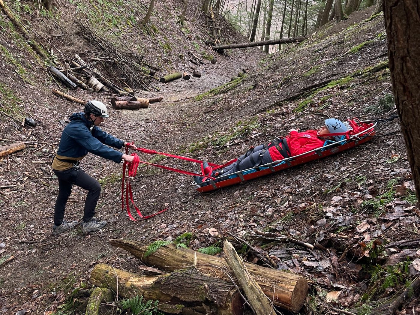 A KSAR member hauls a litter with a volunteer patient up a steep slope
